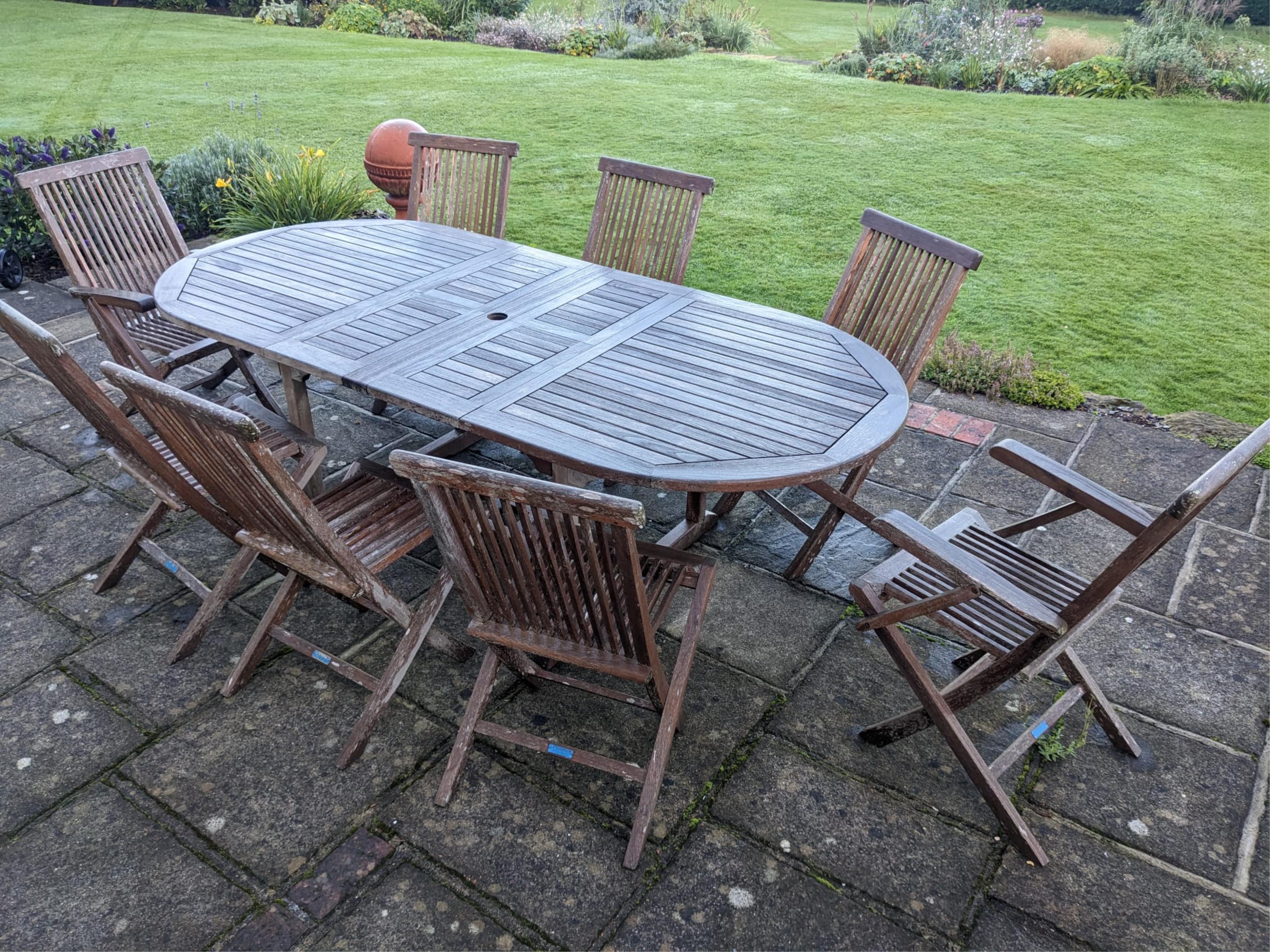 A Lindsay teak extending garden table and eight folding chairs. Condition - weathered, otherwise good